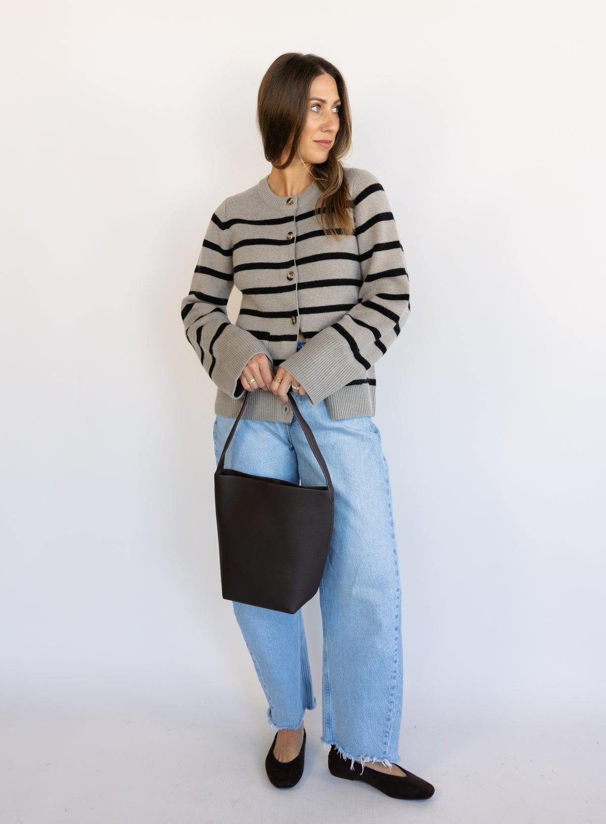 Woman wearing the Hannah Stripe Knit Cardigan, a greige and black striped button-front cardigan