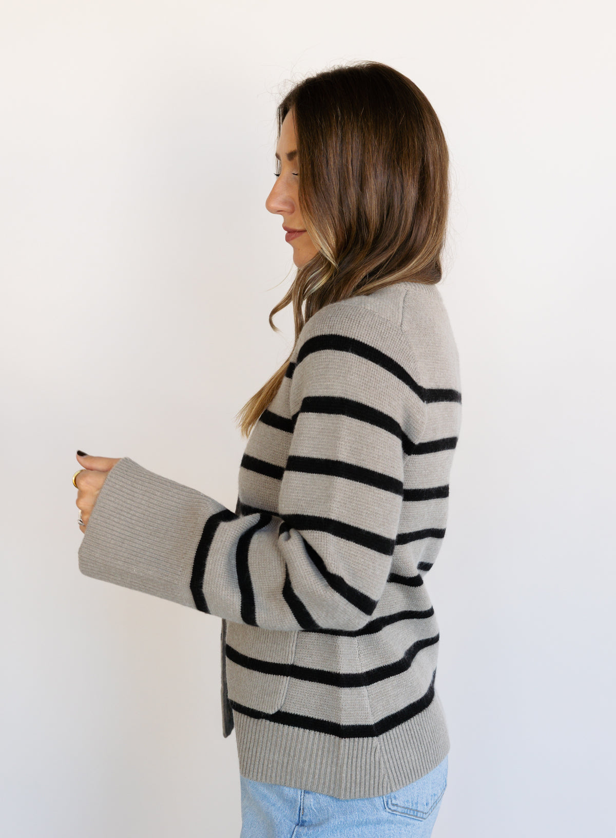 Woman wearing the Hannah Stripe Knit Cardigan, a greige and black striped button-front cardigan