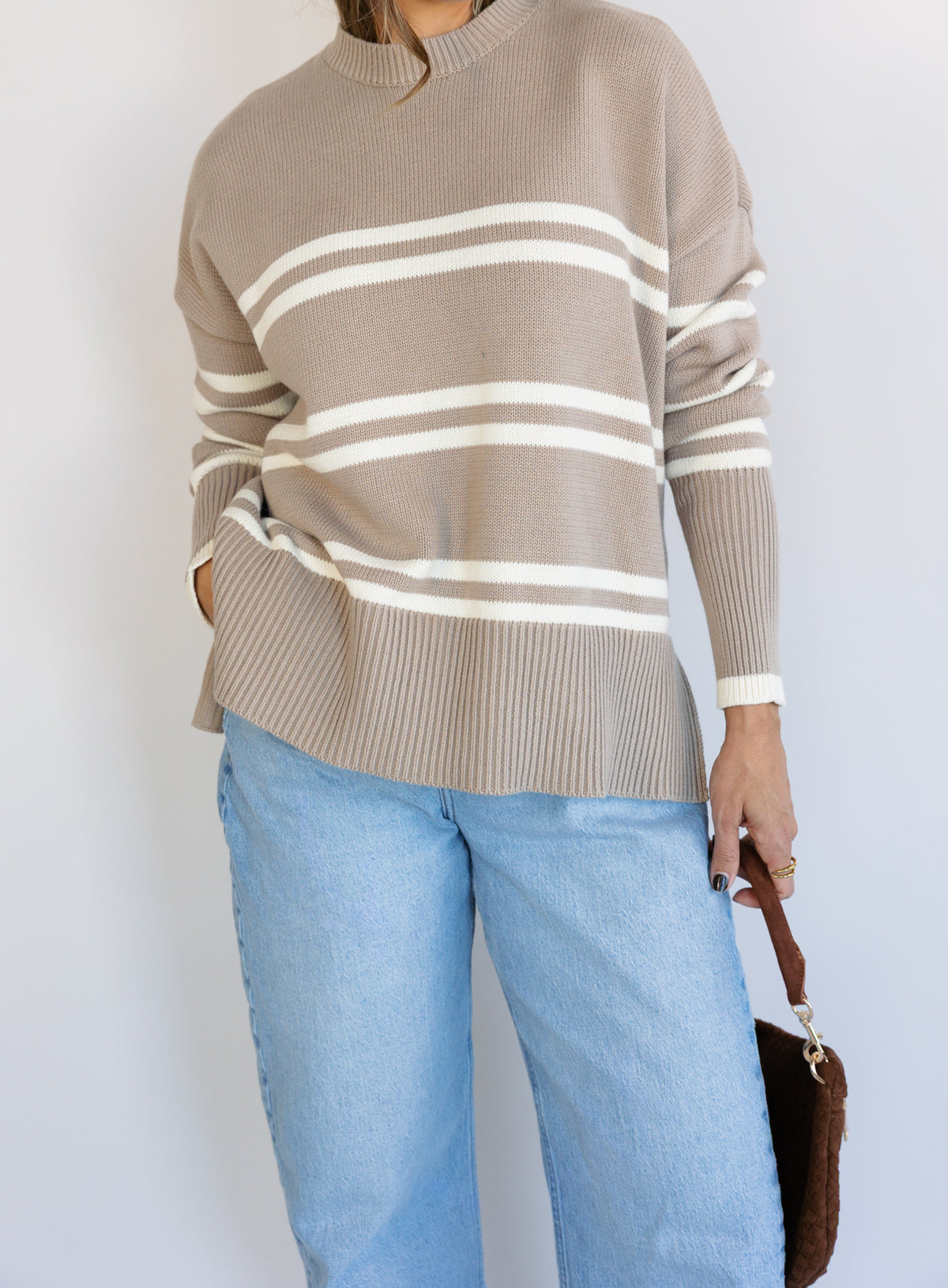 Woman wearing the Lucille Sweater in Taupe, an oversized taupe and cream striped crewneck sweater