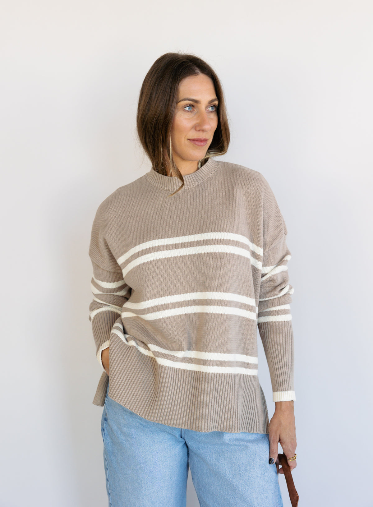 Woman wearing the Lucille Sweater in Taupe, an oversized taupe and cream striped crewneck sweater