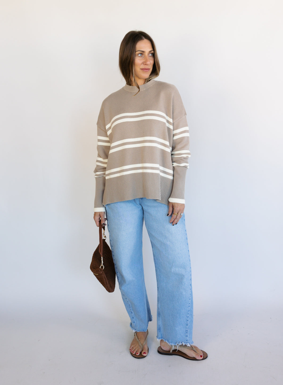 Woman wearing the Lucille Sweater in Taupe, an oversized taupe and cream striped crewneck sweater