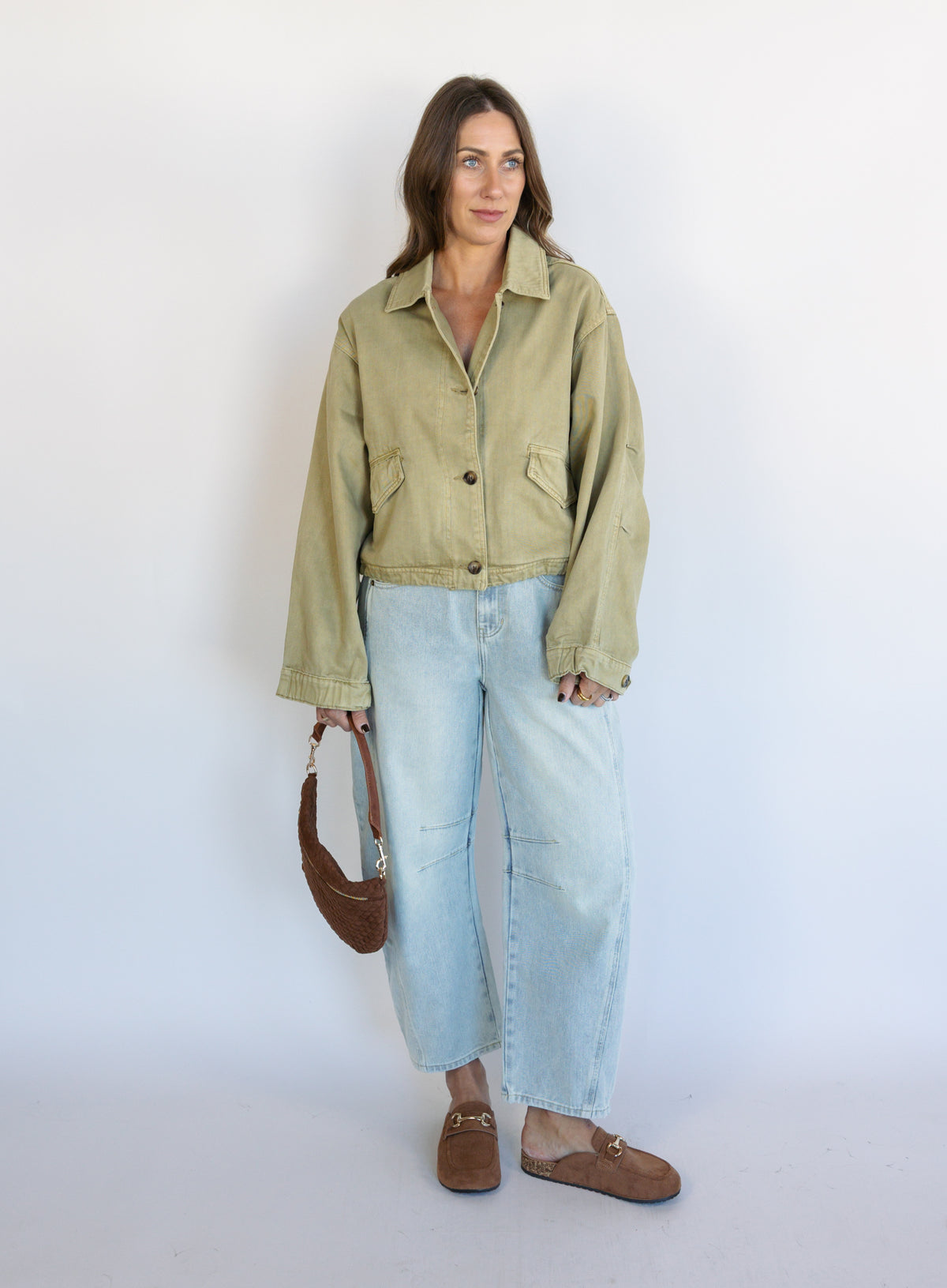 Woman wearing the Zuri Denim Jacket, a light olive cropped cotton twill utility jacket