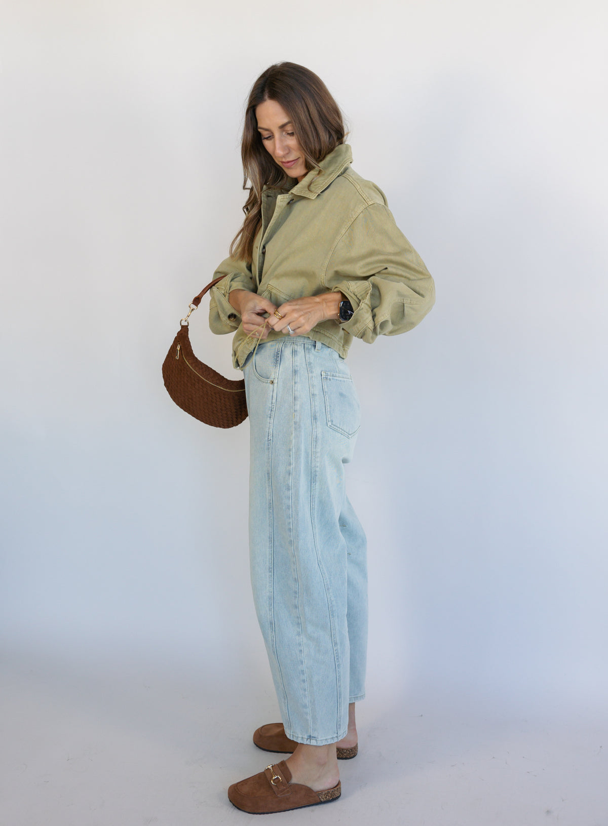 Woman wearing the Zuri Denim Jacket, a light olive cropped cotton twill utility jacket