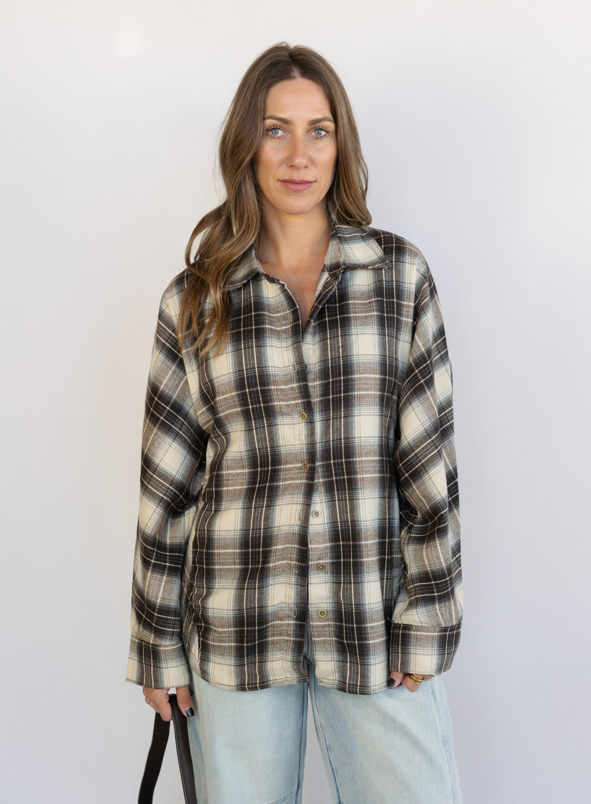 Woman wearing the Heartloom Bobbie Shirt, a black, cream and grey plaid oversized button-down
