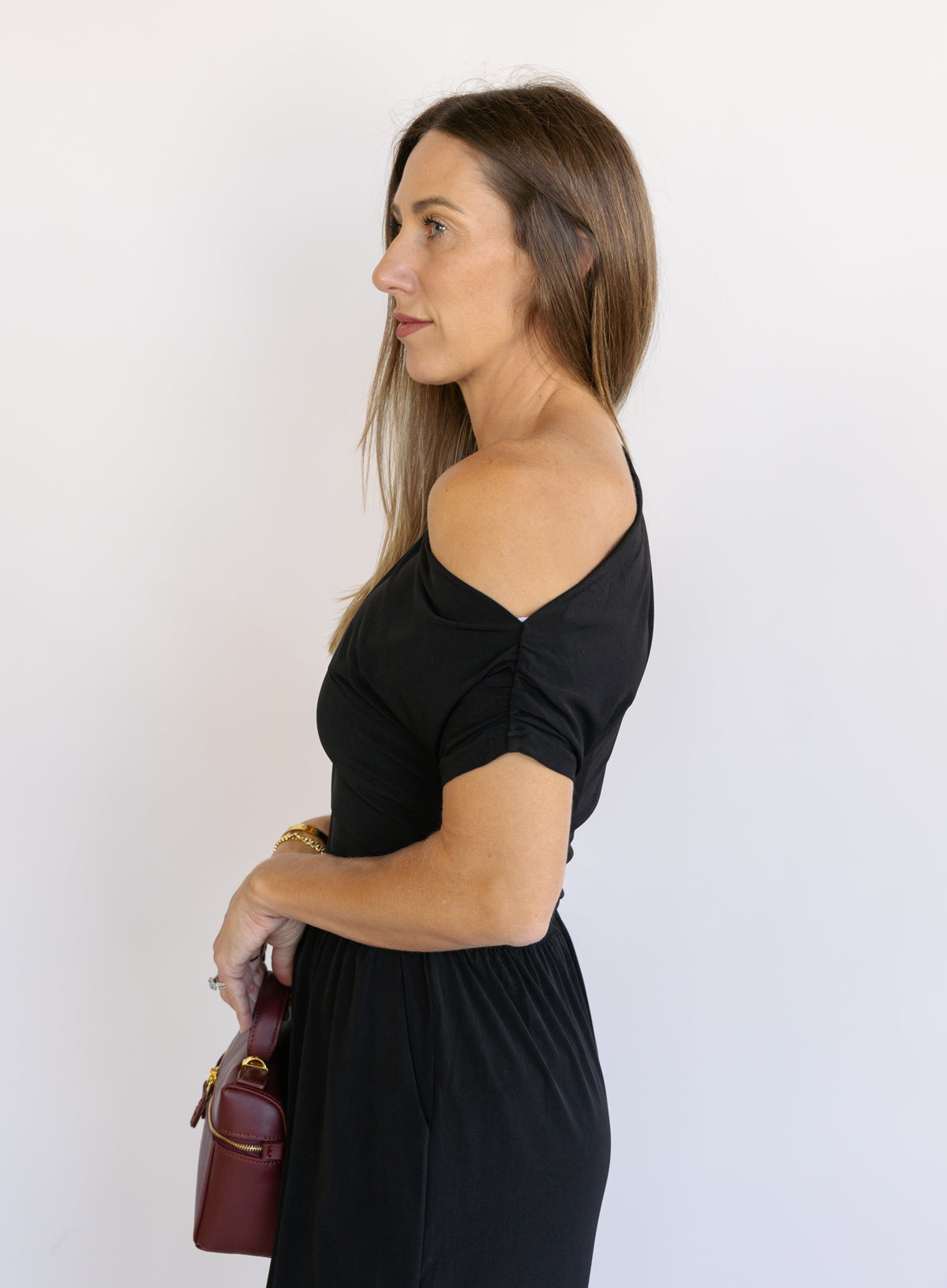 Woman wearing the Azalea One Shoulder Top, a black off-the-shoulder top with a cinched waist