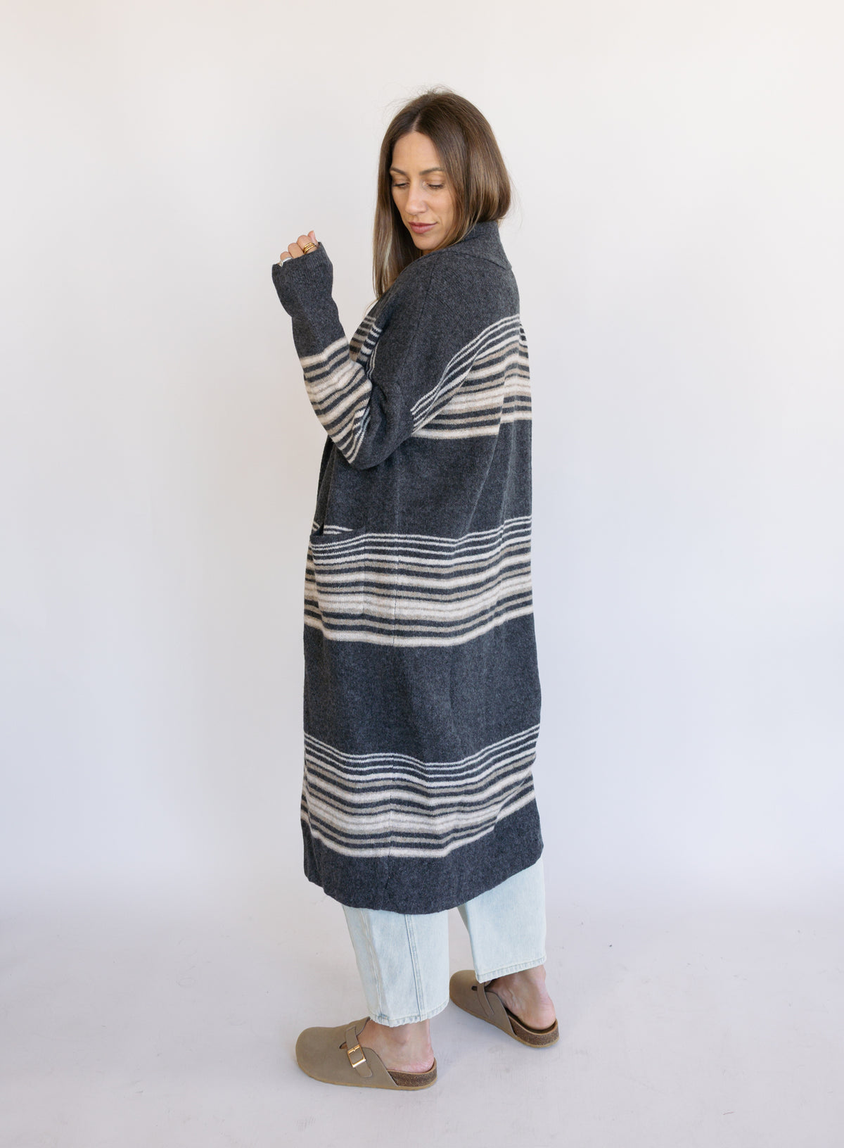 Woman wearing the Linnea Striped Sweater Coat, a long charcoal knit coat with cream and taupe stripes