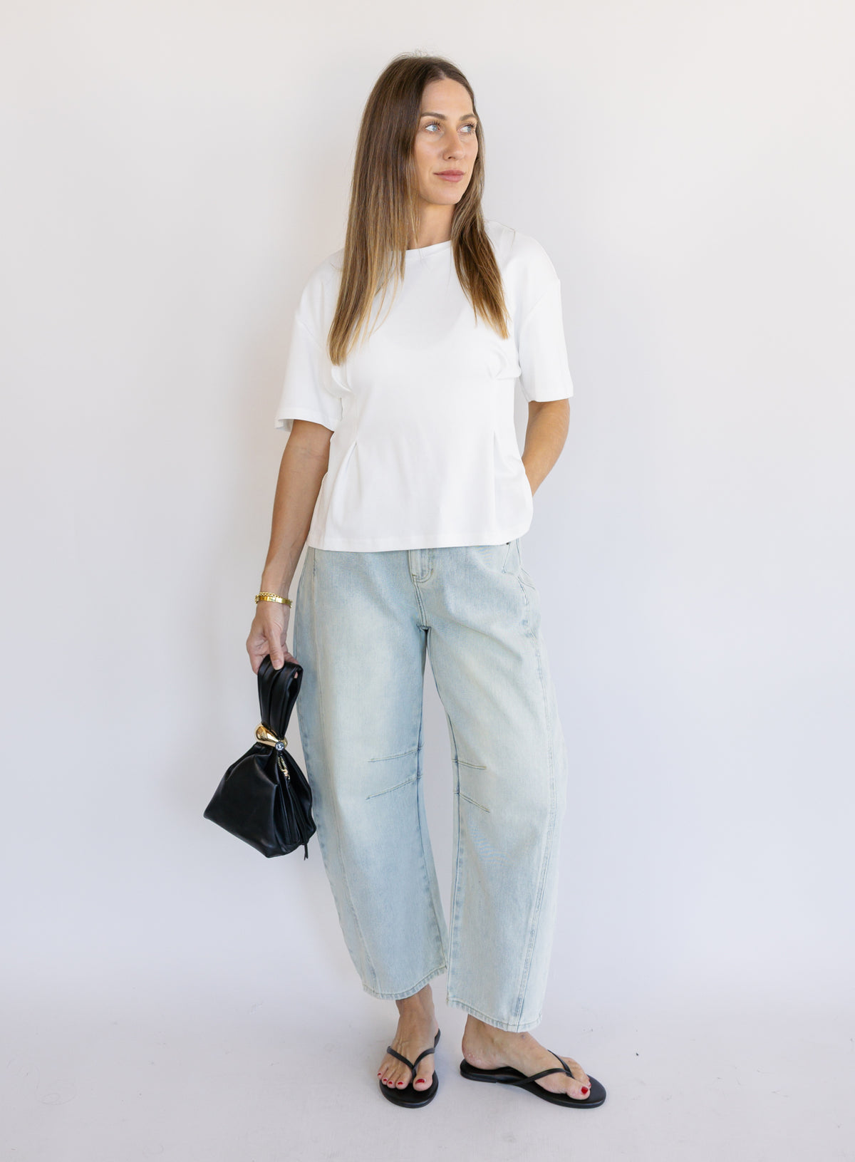 Woman wearing the Lakelyn Cinched Top, a white structured knit crewneck tee cinched at the waist