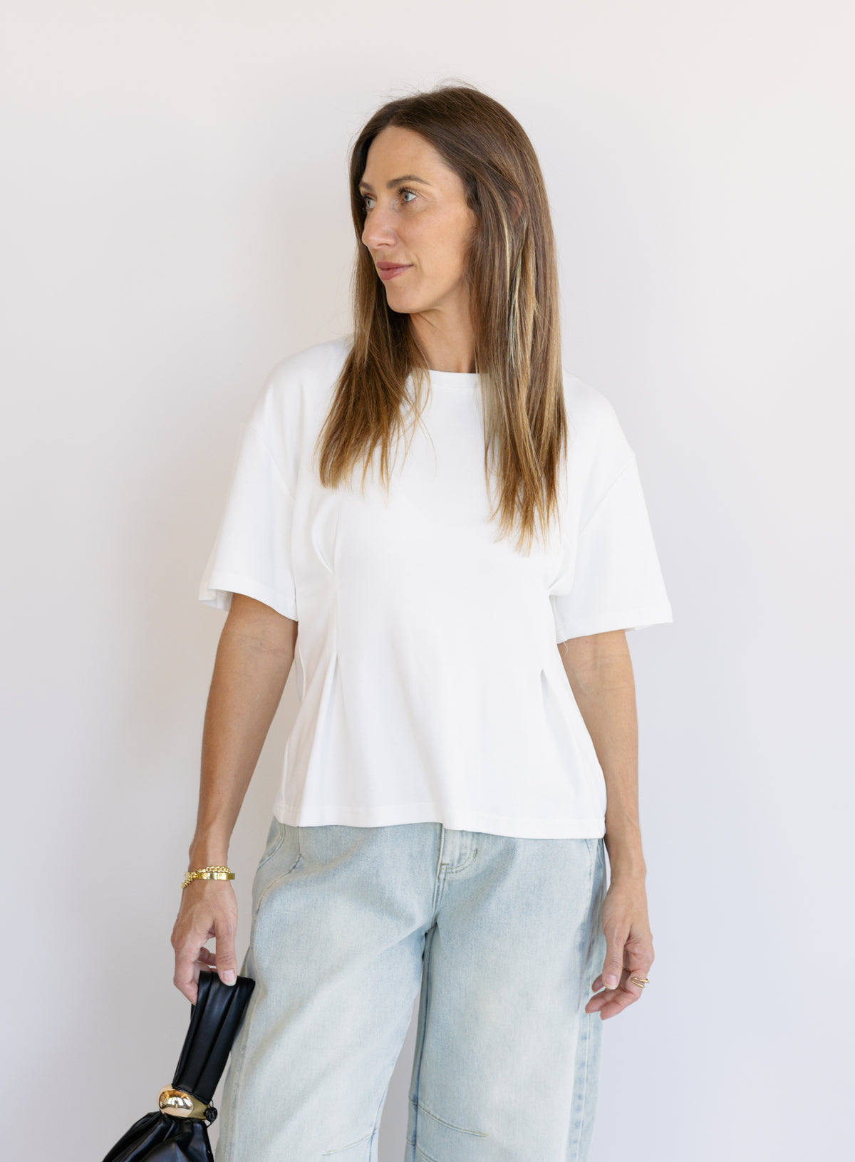 Woman wearing the Lakelyn Cinched Top, a white structured knit crewneck tee cinched at the waist