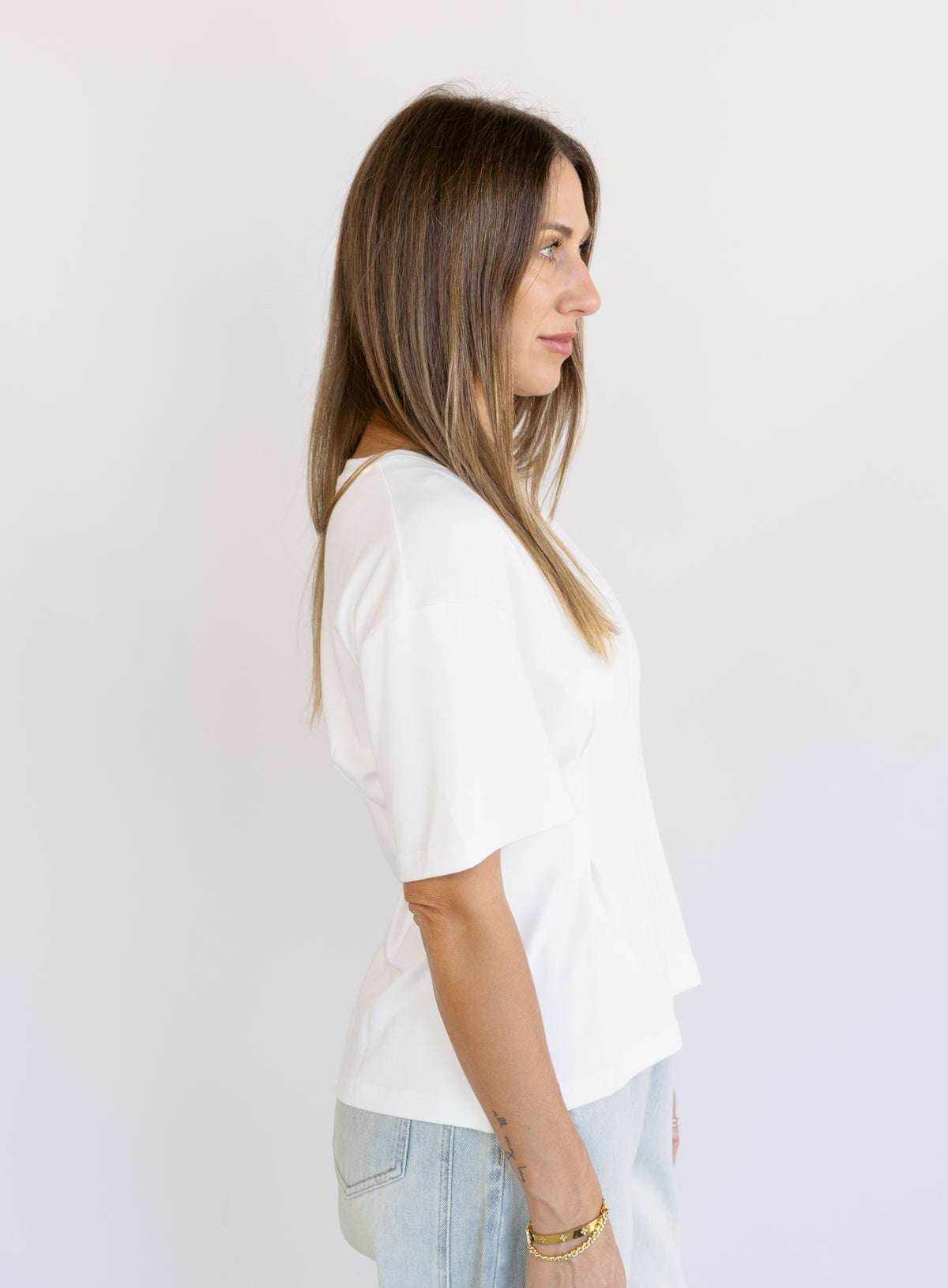 Woman wearing the Lakelyn Cinched Top, a white structured knit crewneck tee cinched at the waist