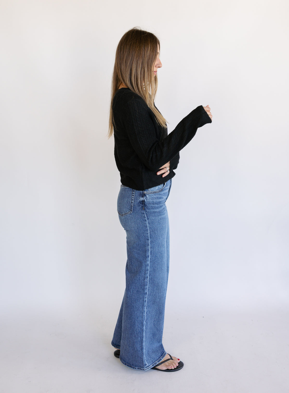 Woman wearing the Z Supply Medina Pointelle Cardigan, a black cable pointelle knit button-front cardigan