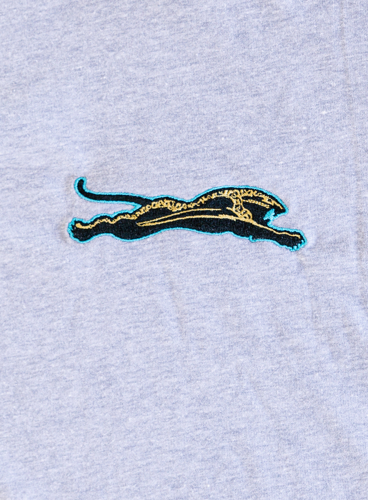 Jags Embroidered Crop Tee, a heather grey crewneck crop tee with a teal and gold embroidered jaguar