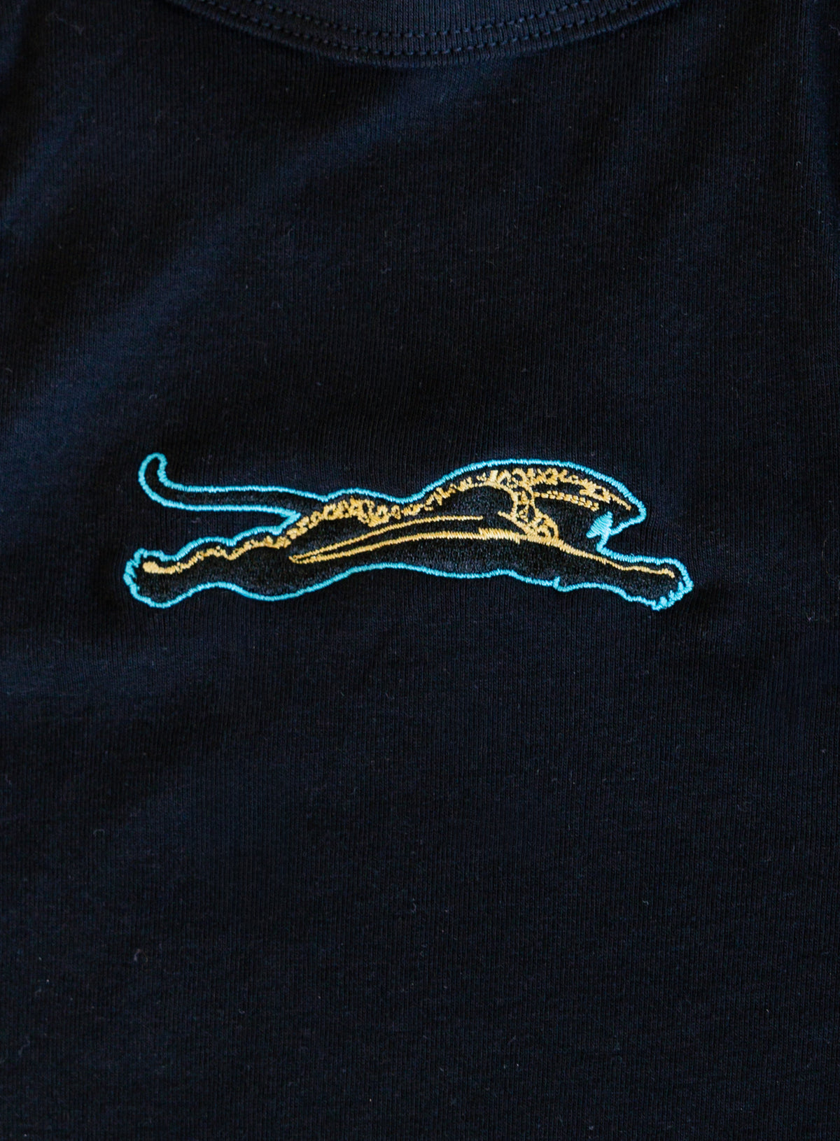 Jags Embroidered Crop Tank, a jet black high-neck crop tank with a teal and gold embroidered jaguar
