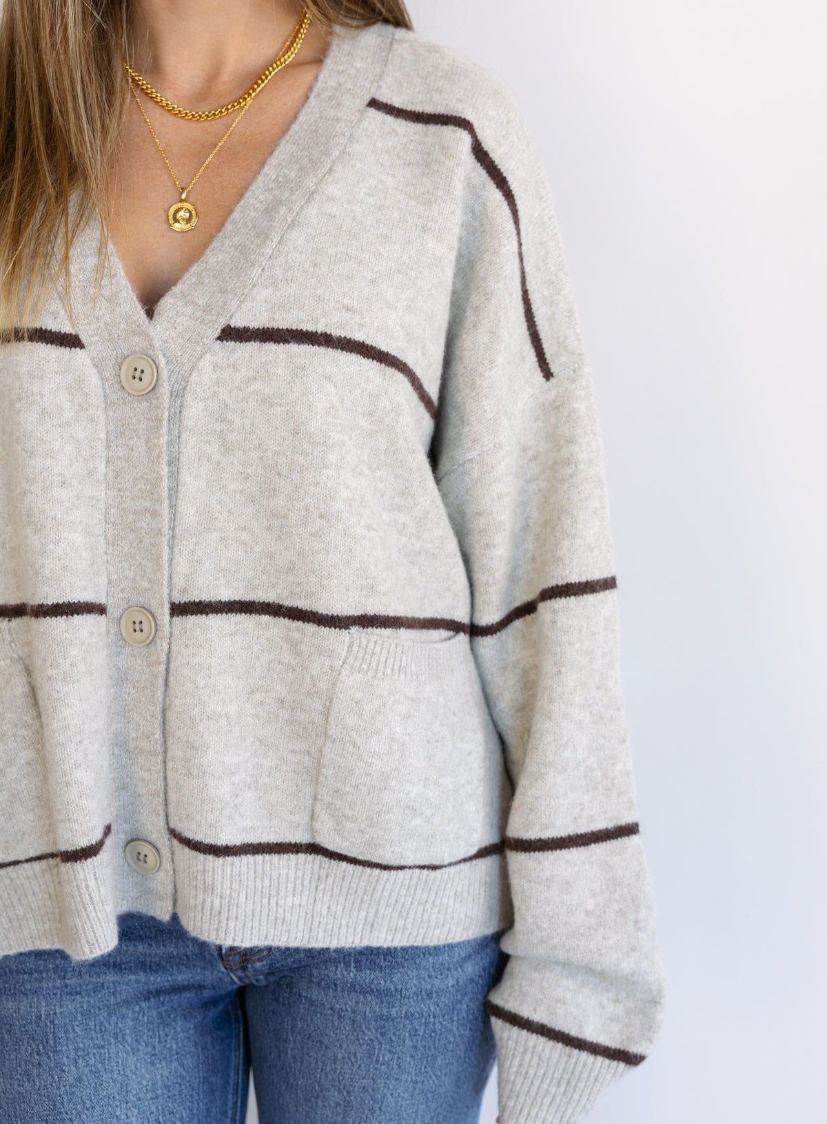 Woman wearing the Juno Striped Knit Cardigan, a mushroom knit cardigan with chocolate stripes and a V-neck