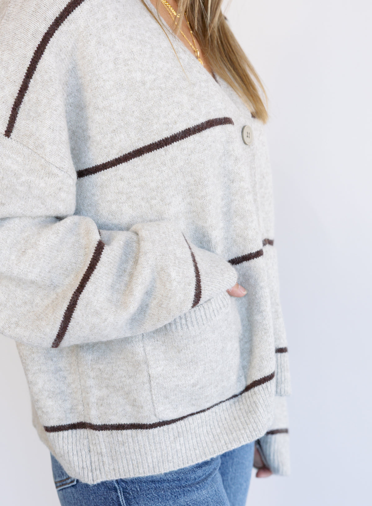 Woman wearing the Juno Striped Knit Cardigan, a mushroom knit cardigan with chocolate stripes and a V-neck