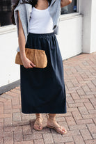 Woman wearing the Cordelia Skirt, a navy maxi skirt with an elastic waist and pockets