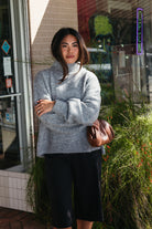 Woman wearing the Audette Sweater, an oversized charcoal heather grey ribbed turtleneck sweater