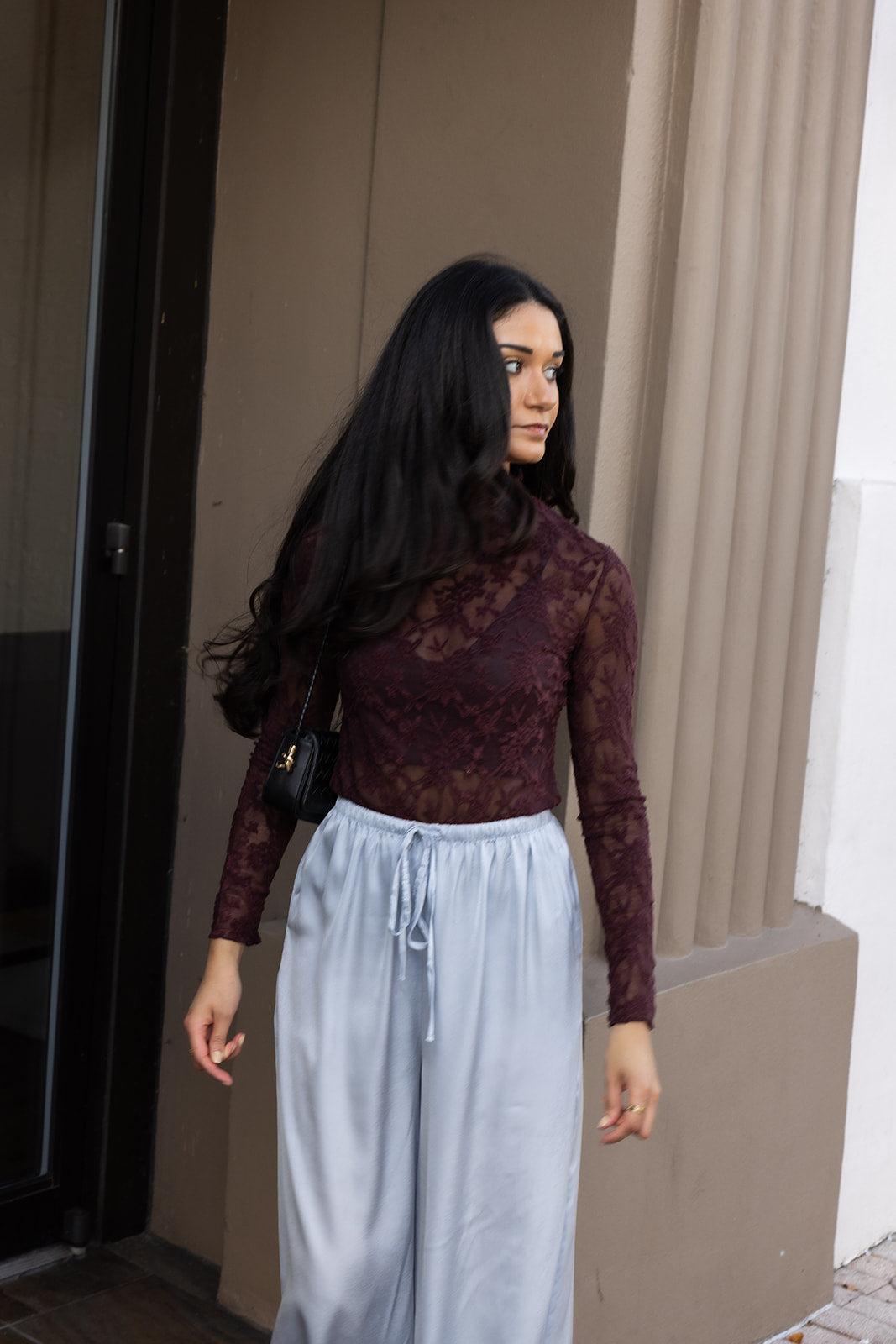 Woman wearing the ASTR The Label Kyra Sheer Mesh Mock Neck Top, a fitted wine top with floral lace detailing