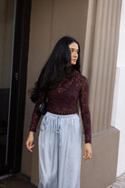 Woman wearing the ASTR The Label Kyra Sheer Mesh Mock Neck Top, a fitted wine top with floral lace detailing