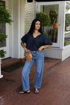 Woman wearing the Cordelia Bubble Hem Top, a navy cropped puff sleeve top with a tie front
