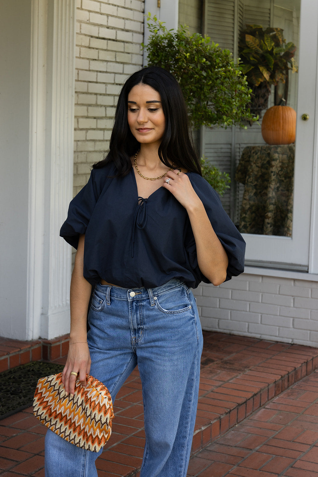 Woman wearing the Cordelia Bubble Hem Top, a navy cropped puff sleeve top with a tie front