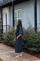 Woman wearing the Cordelia Bubble Hem Top, a navy cropped puff sleeve top with a tie front