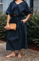 Woman wearing the Cordelia Bubble Hem Top, a navy cropped puff sleeve top with a tie front