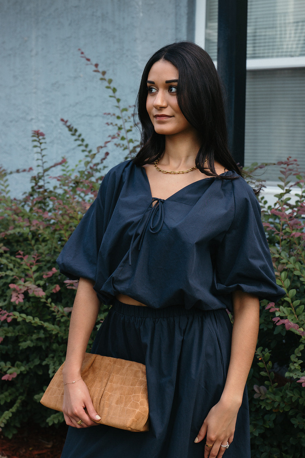 Woman wearing the Cordelia Bubble Hem Top, a navy cropped puff sleeve top with a tie front
