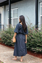 Woman wearing the Cordelia Skirt, a navy maxi skirt with an elastic waist and pockets