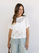 Woman wearing the Lillia Lace Floral Tee, a sheer white mesh tee with floral embroidery