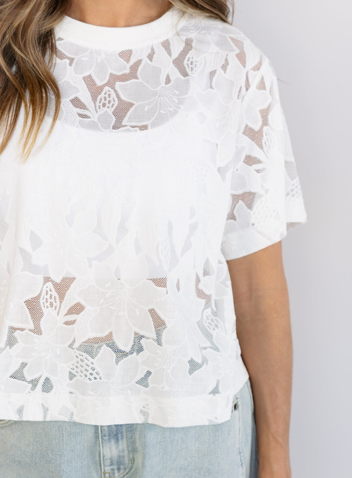 Woman wearing the Lillia Lace Floral Tee, a sheer white mesh tee with floral embroidery