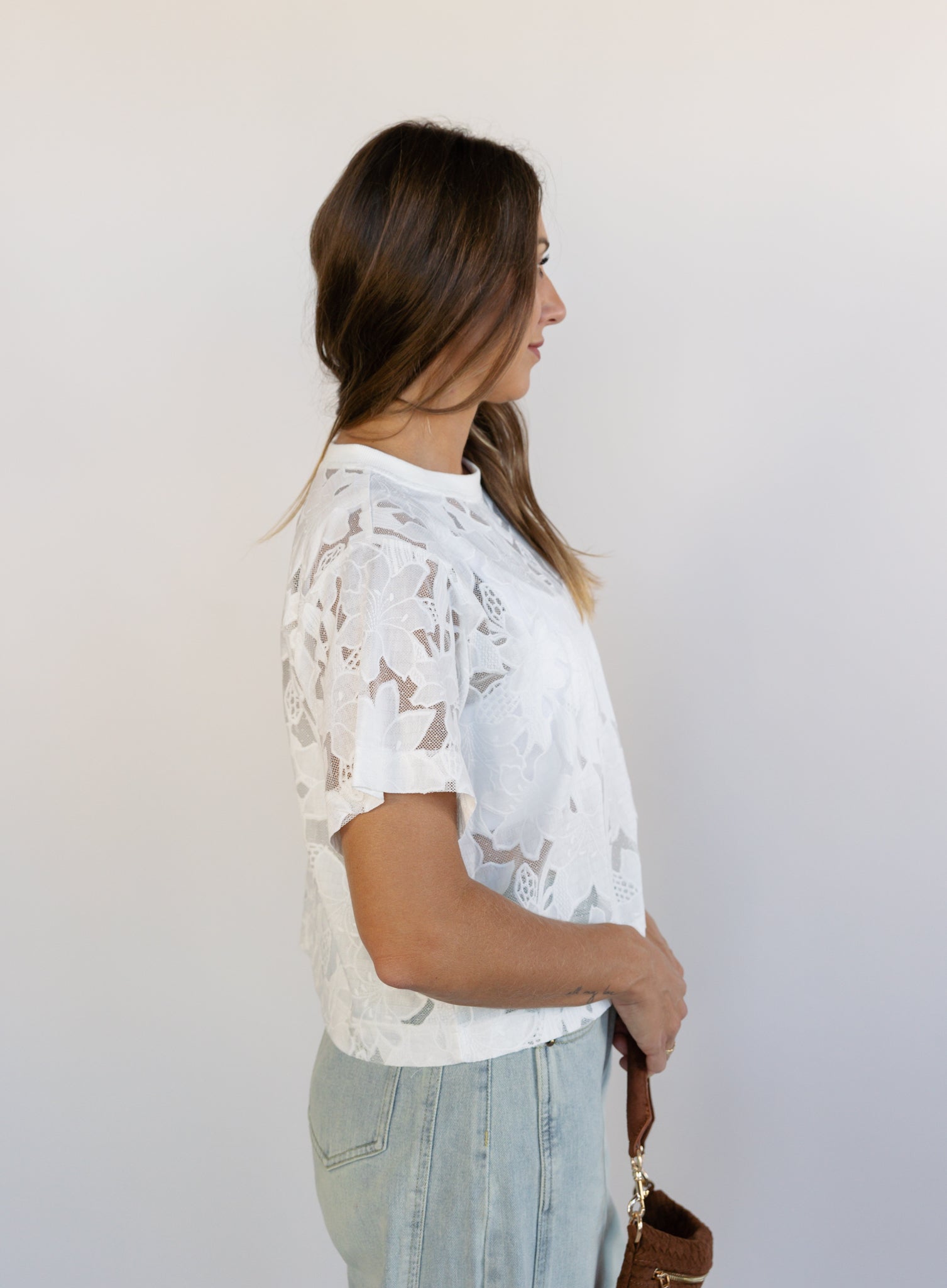 Woman wearing the Lillia Lace Floral Tee, a sheer white mesh tee with floral embroidery