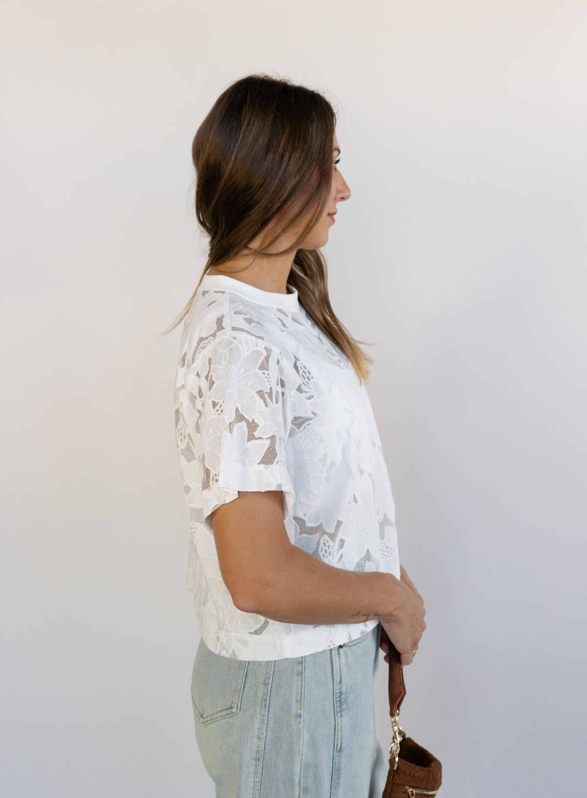 Woman wearing the Lillia Lace Floral Tee, a sheer white mesh tee with floral embroidery