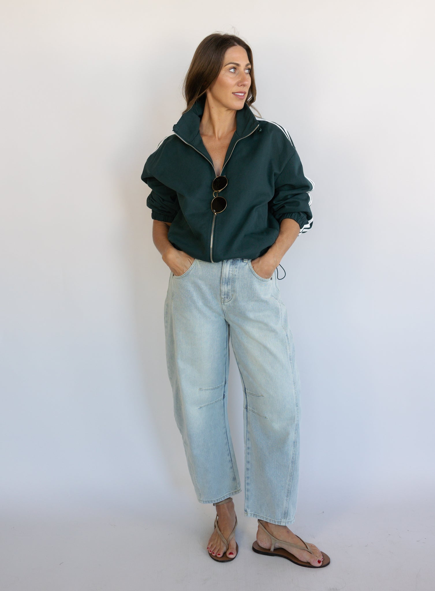 Woman wearing the Marina Twill Track Jacket, a forest green zip-up jacket with white sleeve stripes