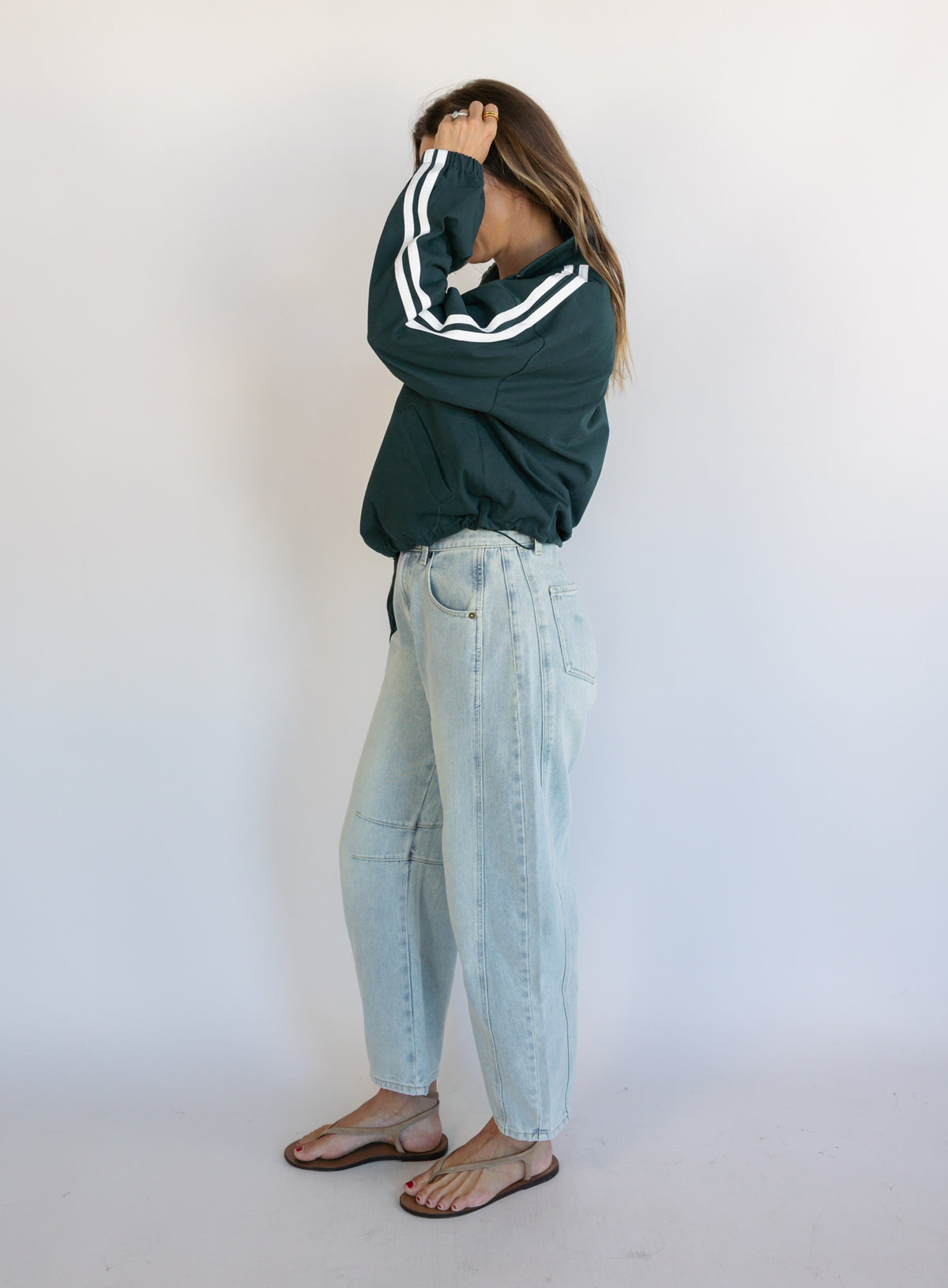 Woman wearing the Marina Twill Track Jacket, a forest green zip-up jacket with white sleeve stripes