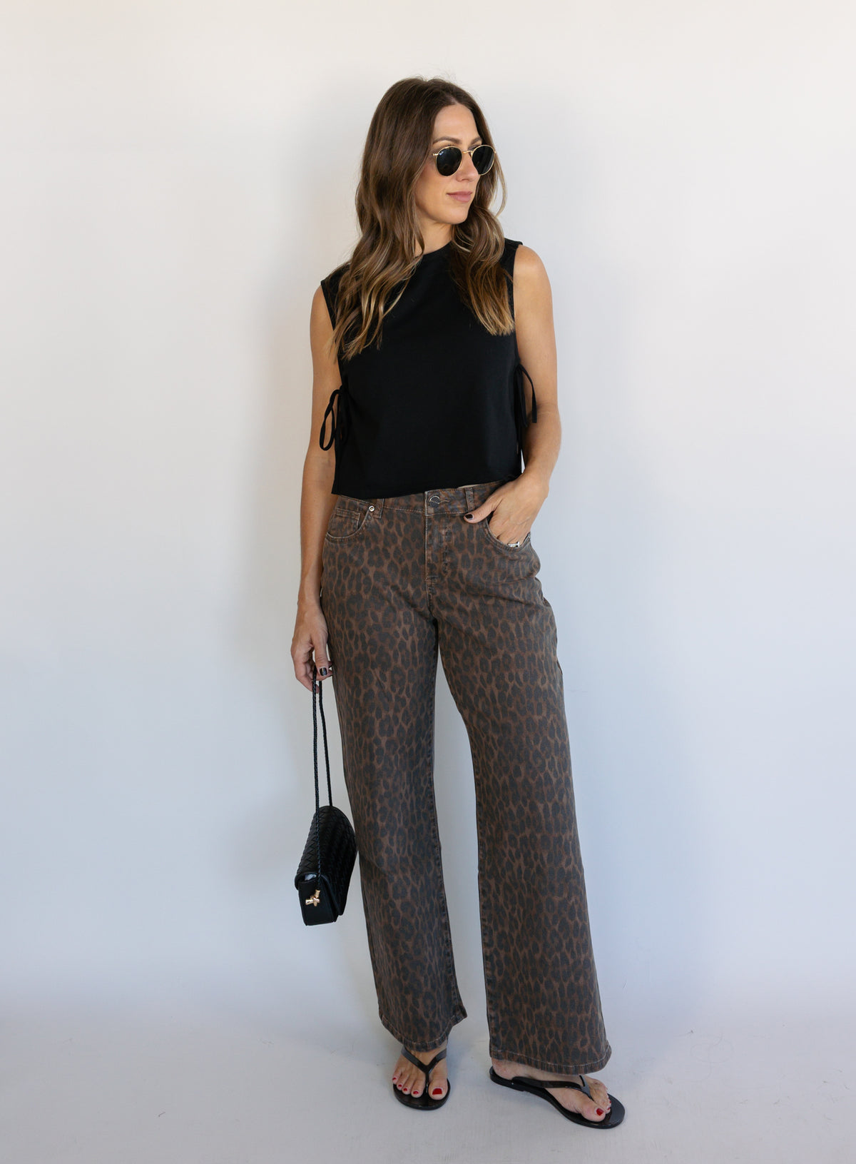 Woman wearing the Dayton Crop Top, a black boxy sleeveless crop top with side ties