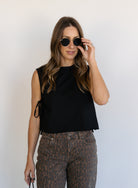 Woman wearing the Dayton Crop Top, a black boxy sleeveless crop top with side ties