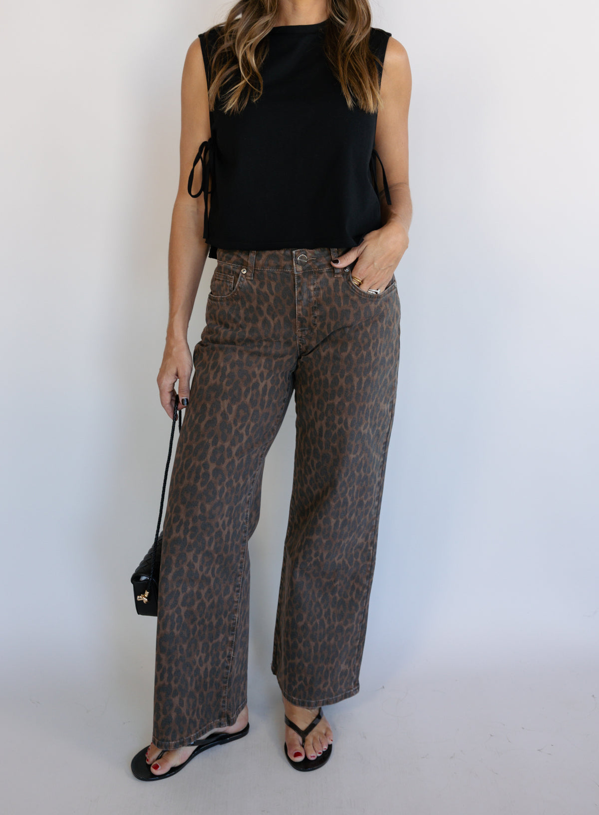 Woman wearing the Dayton Crop Top, a black boxy sleeveless crop top with side ties