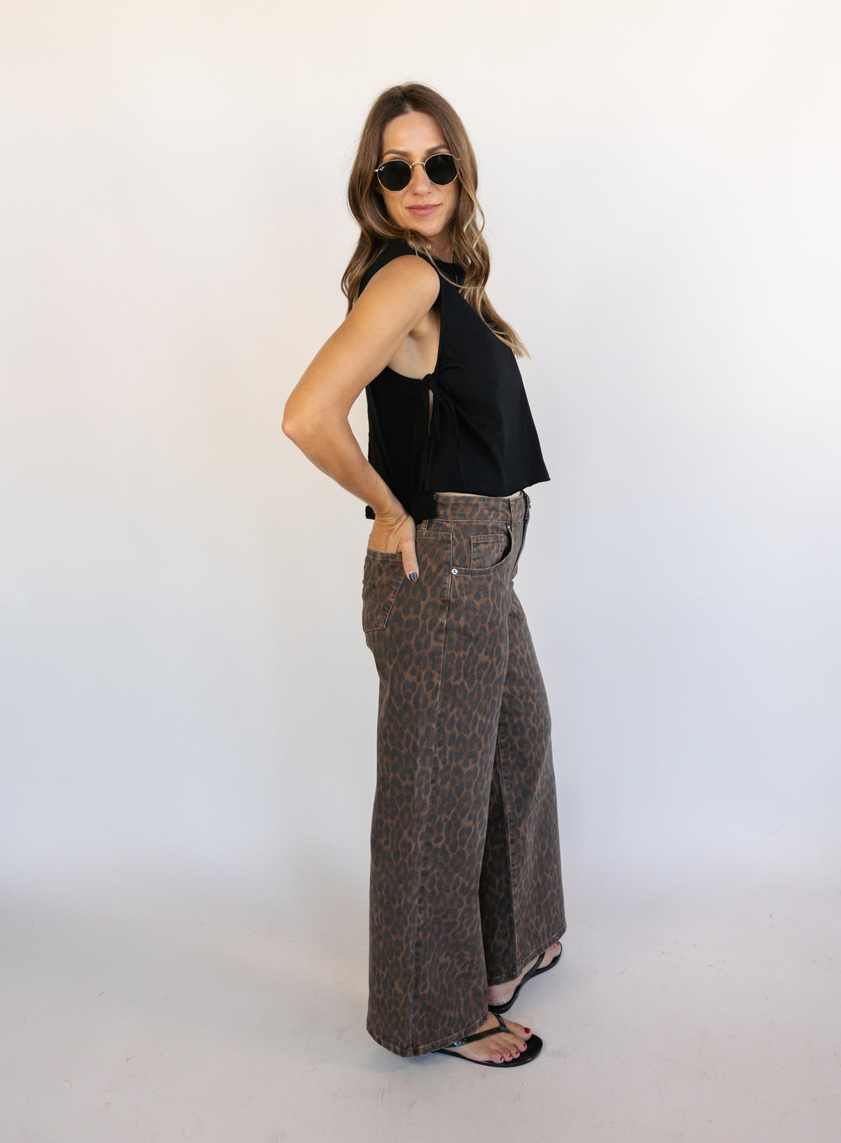 Woman wearing the Dayton Crop Top, a black boxy sleeveless crop top with side ties