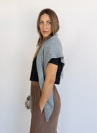 Woman wearing the Wrenley Warm Shawl Scarf in Grey, a heathered grey knit triangle shawl