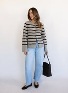 Woman wearing the Hannah Stripe Knit Cardigan, a greige and black striped button-front cardigan