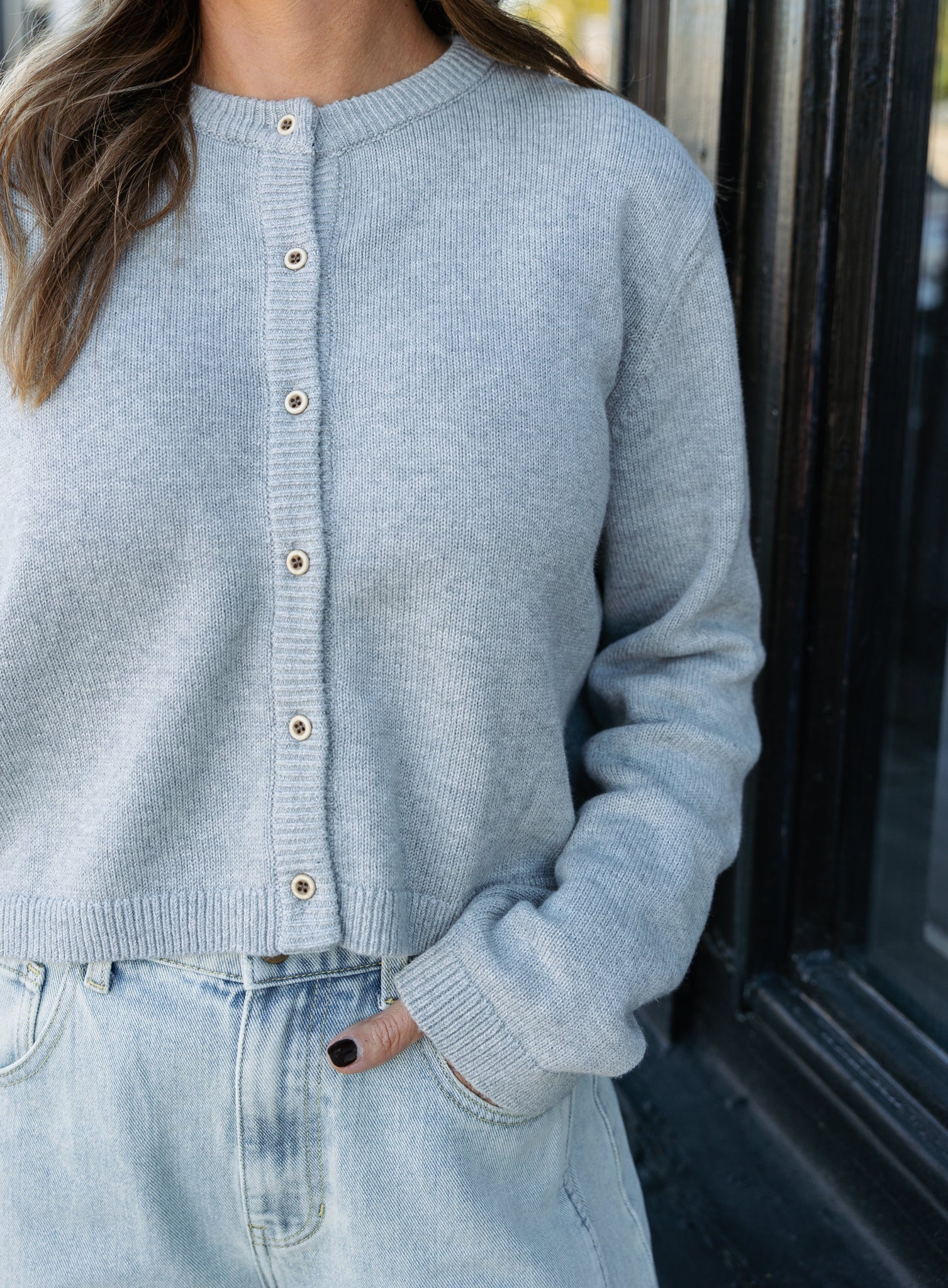 Woman wearing the Cova Cardigan, a grey cropped cotton-wool crewneck cardigan