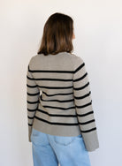 Woman wearing the Hannah Stripe Knit Cardigan, a greige and black striped button-front cardigan