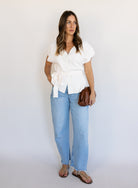 Woman wearing the Yara Belted Top, an ivory V-neck knit top with a detachable belt