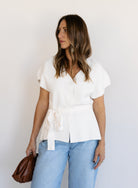 Woman wearing the Yara Belted Top, an ivory V-neck knit top with a detachable belt