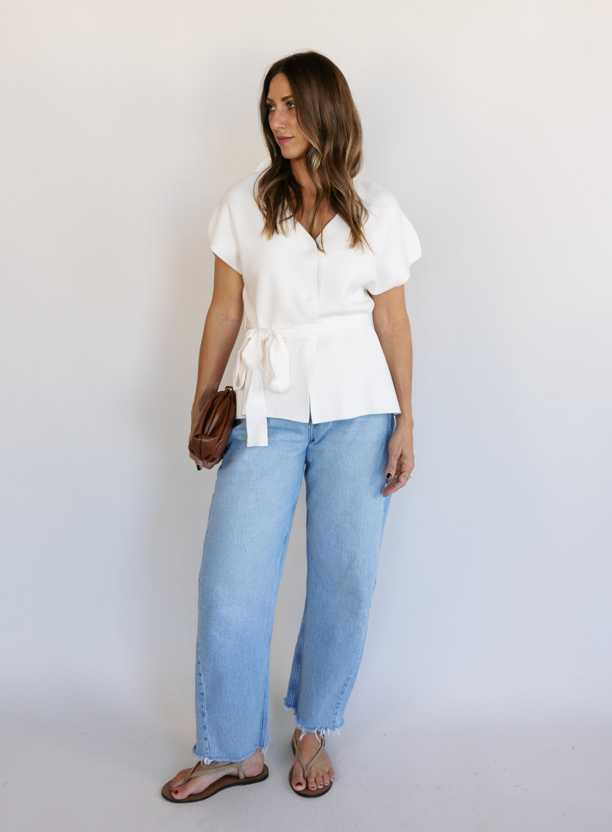 Woman wearing the Yara Belted Top, an ivory V-neck knit top with a detachable belt