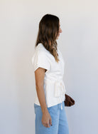 Woman wearing the Yara Belted Top, an ivory V-neck knit top with a detachable belt