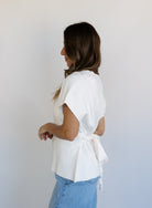 Woman wearing the Yara Belted Top, an ivory V-neck knit top with a detachable belt