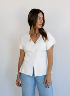 Woman wearing the Yara Belted Top, an ivory V-neck knit top with a detachable belt