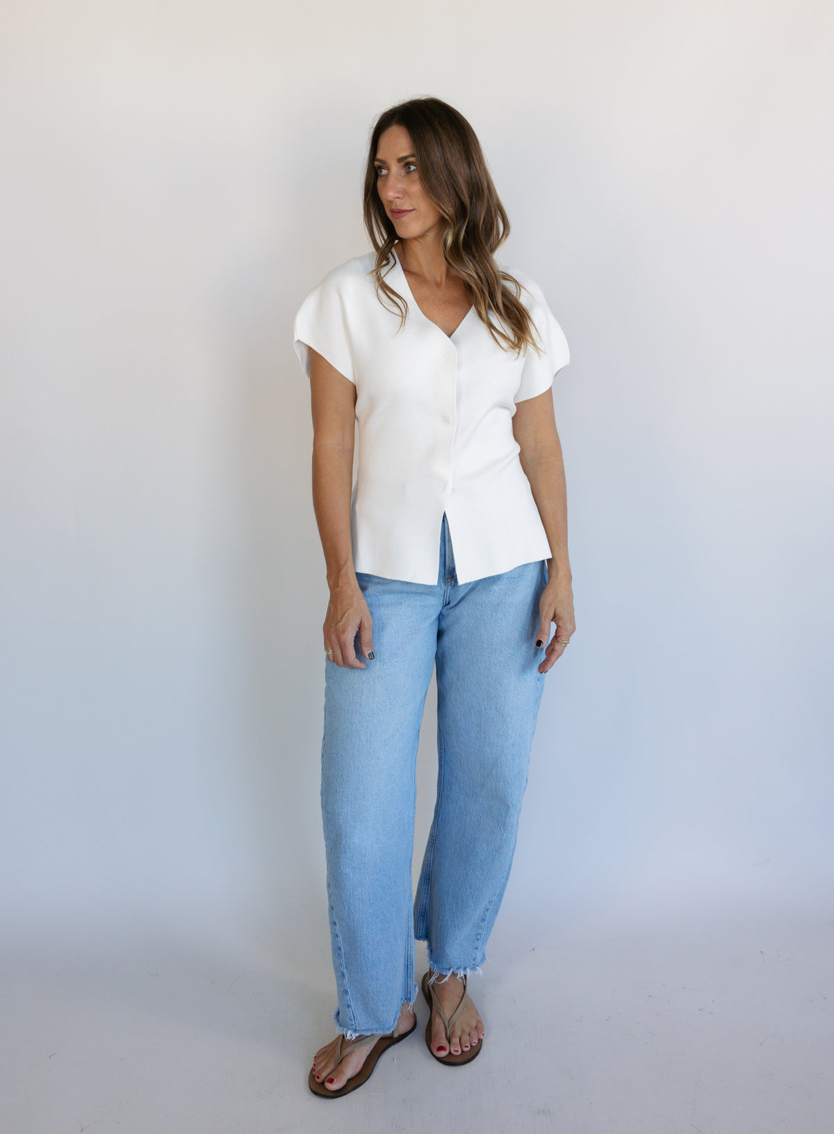 Woman wearing the Yara Belted Top, an ivory V-neck knit top with a detachable belt
