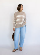 Woman wearing the Lucille Sweater in Taupe, an oversized taupe and cream striped crewneck sweater